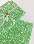 This holiday gift wrap features various kinds of flora printed on a primary green background.