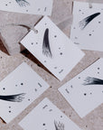 Adelfi letterpressed gift tags scattered across a gray stone background.