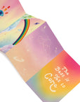 Neon icons postcard pack with variations of design. A pink, yellow, and blue gradient sky with a blue evil eye on top and rainbow-colored streaks. Rainbow clouds with a rainbow and varying neon icons on a pink, yellow and blue gradient sky. Hollow neon icons on a purple and orange ombre background. Rainbow gradient with center-aligned bold text "The Best is Yet to Come" against a white background.