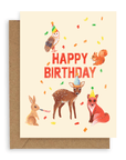 Forest creatures design with confetti, an owl, fox, fawn, rabbit, and squirrel in birthday hats surrounding the words "happy birthday" in red printed on a cream colored background. Shown with kraft envelope.