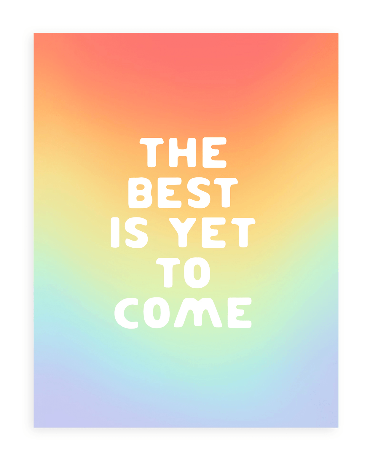 Rainbow gradient background with &quot;The Best Is Yet To Come&quot; in bold, white font printed on cardstock  resting on a white background.