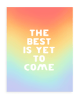 Rainbow gradient background with "The Best Is Yet To Come" in bold, white font printed on cardstock resting on a white background.