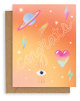 Greeting card with the word "Congrats" across the front in white hollow font with neon icons against an ombre orange background. Shown with brown kraft paper envelope.