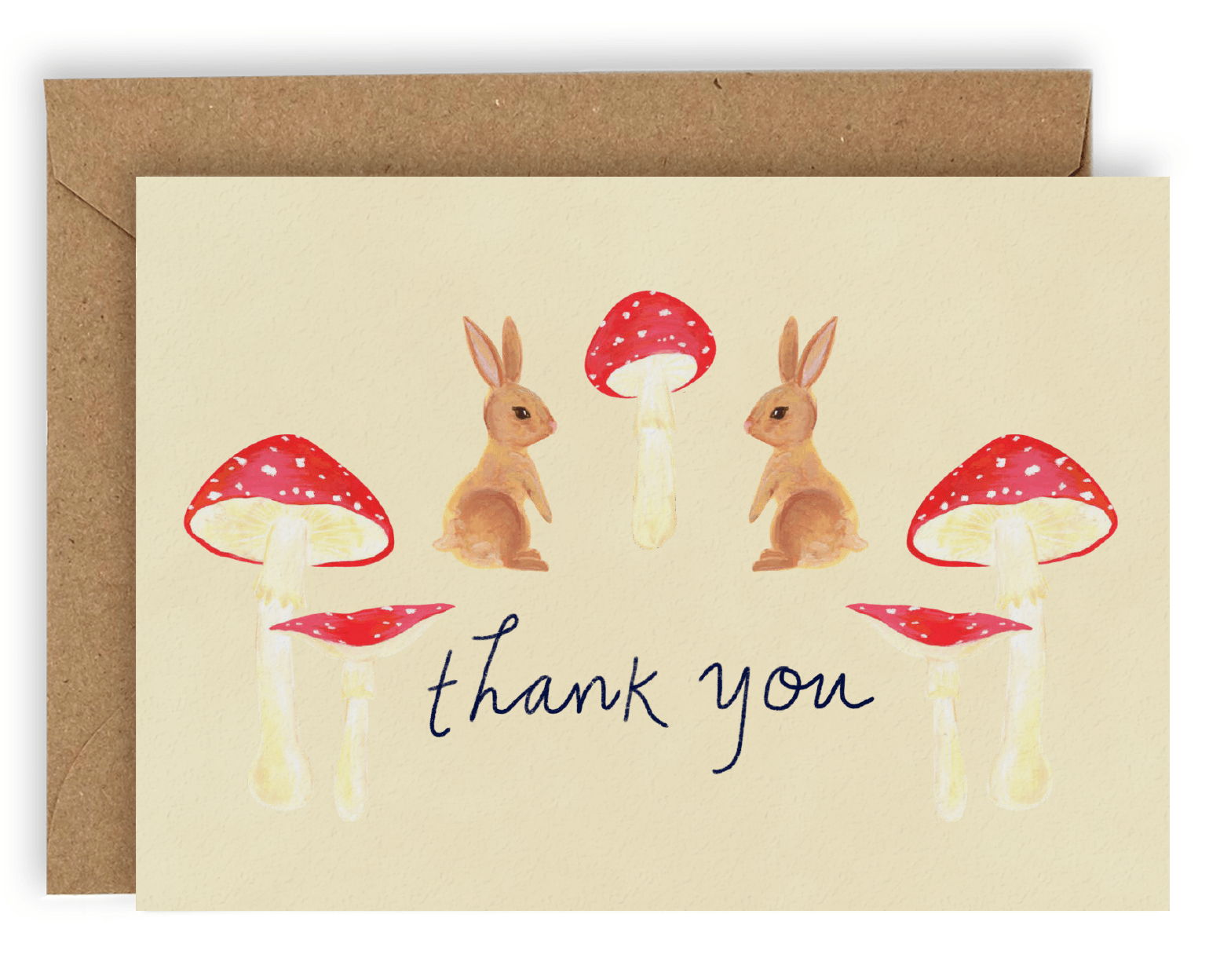 Our new Forest Creatures design! This card features two light brown/dirty blonde rabbits facing each other with a red magic mushroom between them and two red mushrooms on either side of the words &quot;Thank You&quot; printed in black ink on a cream background. Shown with Kraft envelope.