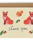 Our new Forest Creatures design with two red/orange foxes facing away from each other with an orange squirrel between them facing left with an Acorn in its hands. Below are the words "Thank You" printed in cursive black ink with two stems of Acorns on either side and a stem of an acorn above. Printed on a cream colored background. Shown With Kraft envelope.
