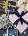 A pile of presents wrapped in assorted Adelfi gift wraps with bows. 