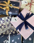 A pile of presents wrapped in assorted Adelfi gift wraps with bows.