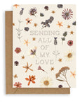 "Sending All Of My Love" pointillism text font design aligned in the center of the cream colored card surrounded by pressed flowers printed on cardstock with a kraft envelope.