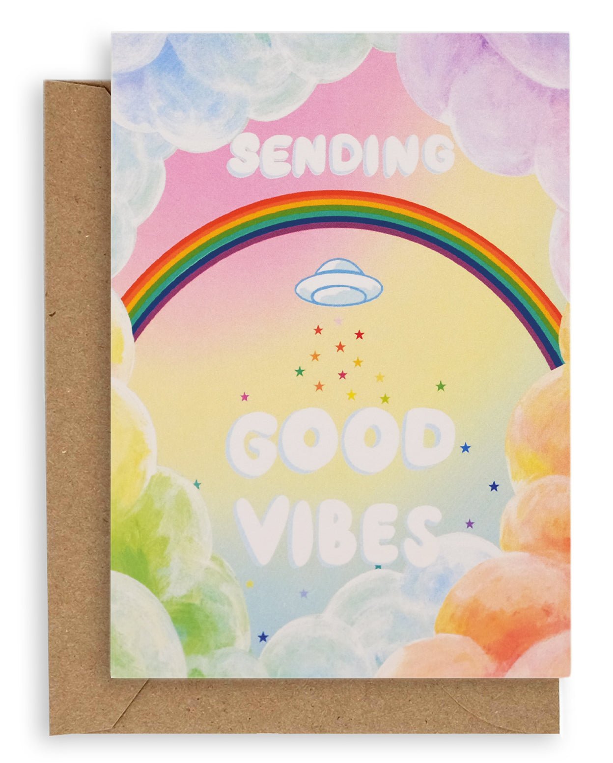 Colorful greeting card with cumulus clouds surrounding a rainbow with a UFO below it, followed by rainbow stars and clouds, and the words "Sending Good Vibes" on the front. Shown with a brown kraft paper envelope.