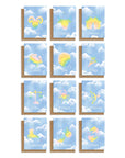 Adelfi Horoscope cards have a light blue background with white clouds and each of the twelve horoscope symbols painted in pastel rainbow colors. Shown with kraft envelope.