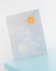 Blue sky with sun, moon, stars and text that reads "My Sun, Moon, + Stars." Shown on blue shelf with white background.