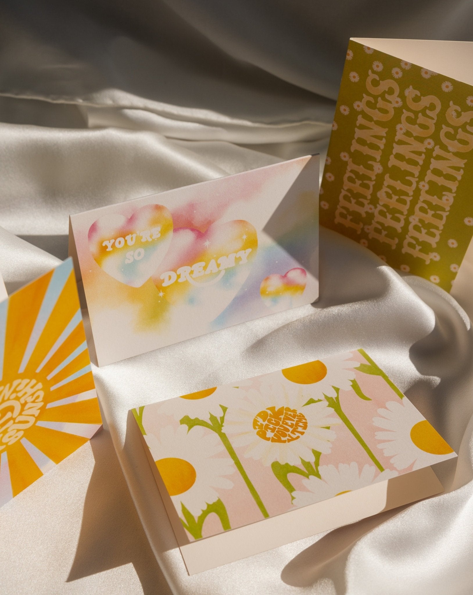 Four Love Notes cards on a white silk background.