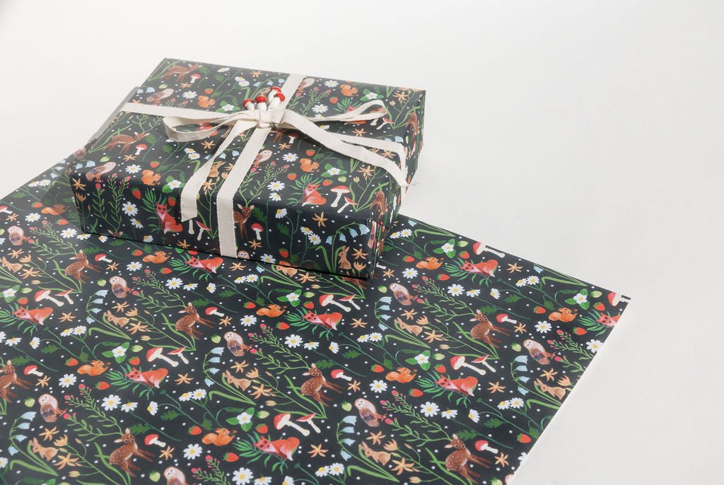 Our exciting new Holiday gift wrap features a stunning array of forest animals and flora. There are Owls, Deer, Rabbits, Squirrels, Foxes, Mushrooms, berries and various kinds of flora with orange, white, red, blue, and yellow blooms printed on a carbon black background.