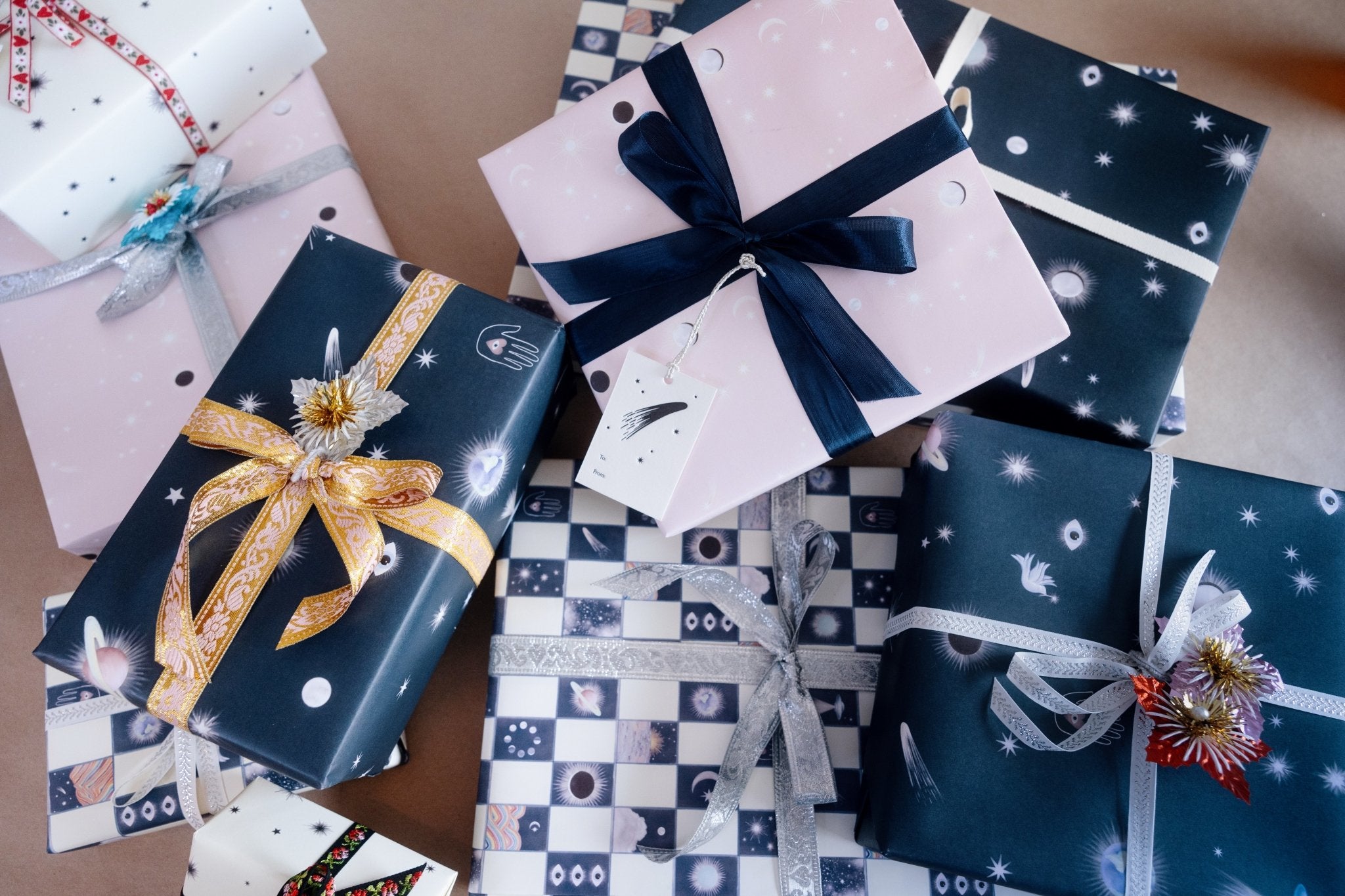A pile of presents wrapped in assorted Adelfi gift wraps with ribbons. 