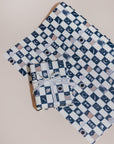 A present wrapped in gift wrap with a navy blue and cream checkerboard pattern. The navy boxes are filled with mystical icons, placed on a single flat sheet of the same gift wrap.