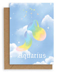Aquarius Horoscope card with a kraft envelope. The horoscope symbol is painted in rainbow pastel on a blue background with white clouds. 