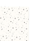 A sheet of gift wrap with a cream background scattered with black comets, shooting and still stars.