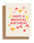 Cream colored card with pink, orange and red mushrooms mushrooms and red printed text with the words "Have A Magical Birthday" in the middle. Shown with kraft envelope.