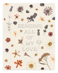 "Sending All Of My Love" pointillism text font design aligned in the center of the cream colored card surrounded by pressed flowers printed on cardstock against a white background.