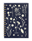 A photo of a notebook cover with cream flower and leaf outlines on a navy blue background with the words "planner" in caps-lock text at the bottom. 